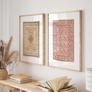 Könnte beinhalten: Zwei gerahmte, rechteckige Wandkunstwerke. Eines zeigt ein beige-grünes Blumenmuster, das andere ein rosa-rotes Blumendesign. Beide sind in hellem Holz gerahmt und hängen an einer weißen Wand. Die Kunstwerke befinden sich über einem Holztisch mit Büchern und dekorativen Gegenständen.