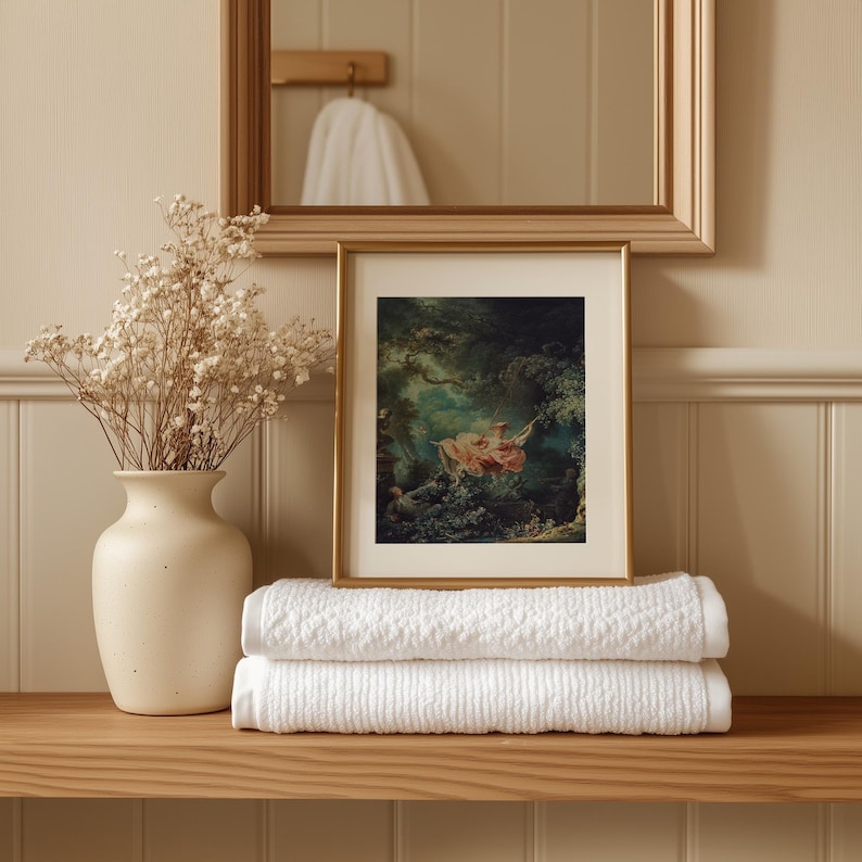 Fragonard The Swing French Rococo painting giclée print, small gold float frame white mat, displayed on folded white towels oak bathroom shelf, cream ceramic vase dried baby's breath gypsophila, elegant romantic bathroom wall art