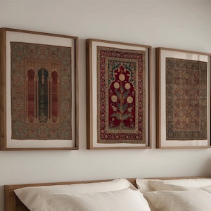 May include: Three framed vintage textile art pieces. The artwork features intricate patterns in shades of red, green, and brown, set against a neutral background. The wooden frames add a touch of warmth to the wall decor.
