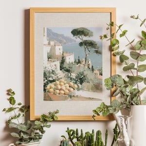 Amalfi Coast lemon terrace and umbrella pine Italian art print in a natural light wood frame mounted on a white wall surrounded by trailing eucalyptus, potted cacti, and succulent plants — loose impressionist oil-style painting of white Amalfi architecture, sea view and a bowl of lemons