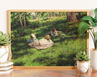 May include: A framed print of an oil painting depicting three figures resting on a grassy hillside under trees. One figure lies on a blanket reading, while two others sit nearby on the green lawn. The scene is illuminated by dappled sunlight.