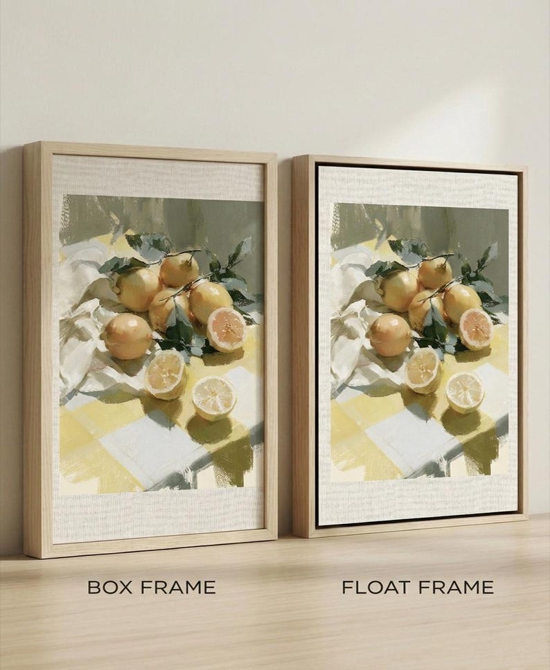 May include: Two framed art prints featuring a still life of lemons. The artwork depicts whole and sliced lemons with green leaves on a yellow and white checkered surface. The frames are labeled "BOX FRAME" and "FLOAT FRAME".