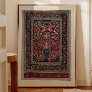 Könnte beinhalten: Gerahmter Wandteppich im Vintage-Stil mit goldenem Rahmen. Der Wandteppich zeigt ein zentrales Vasenmuster mit Blumen- und Vogelmotiven in Rot, Blau und Gold. Der Rand hat ein sich wiederholendes Blumenmuster.