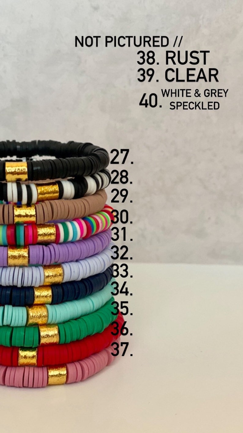 Puede incluir: Una pila de pulseras coloridas con detalles dorados. Las pulseras est&aacute;n hechas de cuentas redondas y est&aacute;n apiladas en una variedad de colores, incluyendo negro, blanco, marr&oacute;n, rosa, rojo, verde, azul y morado. El texto "NOT PICTURED // 38. RUST 39. CLEAR 40. WHITE & GREY SPECKLED" es visible sobre las pulseras.