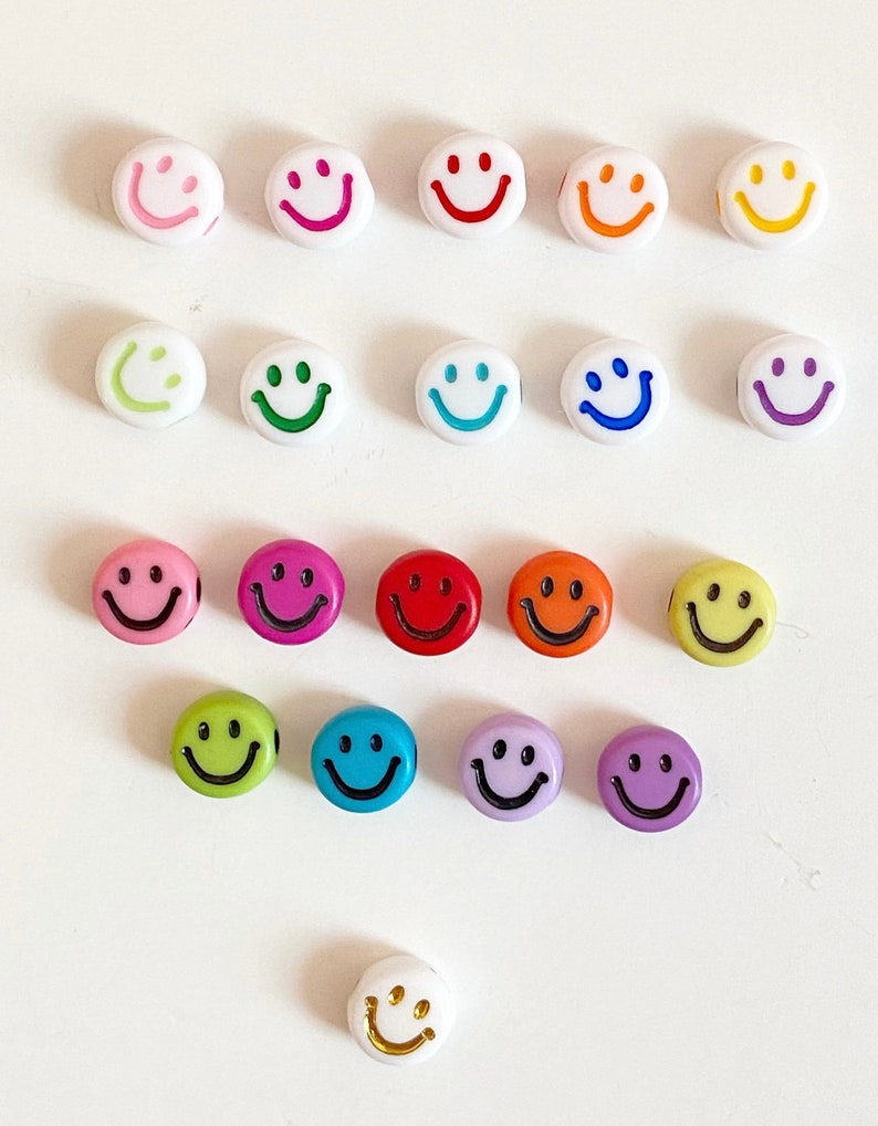Puede incluir: Surtido de cuentas de caritas sonrientes de colores con contornos negros. Las cuentas son de pl&aacute;stico y vienen en una variedad de colores, incluyendo amarillo, naranja, rojo, rosa, morado, azul, verde y blanco.