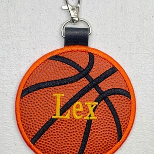 May include: Orange and black basketball keychain with the name "Lex" embroidered in yellow thread.