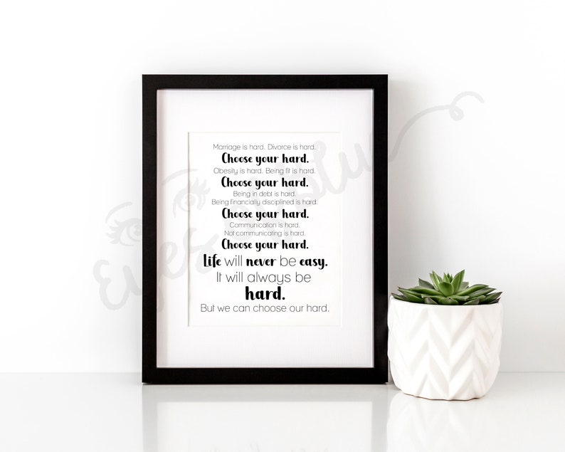 May include: A black framed print with a white background and black text that reads: "Marriage is hard. Divorce is hard. Choose your hard. Obesity is hard. Being fit is hard. Choose your hard. Being in debt is hard. Being financially disciplined is hard. Choose your hard. Communication is hard. Not communicating is hard. Choose your hard. Life will never be easy. It will always be hard. But we can choose our hard."