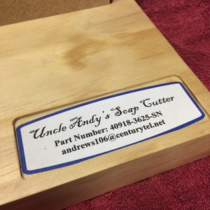 May include: A wooden soap cutter with a blue and white label that reads "Uncle Andy's Soap Cutter", "Part Number: 40918-3625-SN", and "andrews106@centurytel.net".
