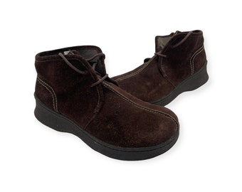 May include: A pair of brown suede ankle boots with laces. The boots have a rounded toe and a thick sole.