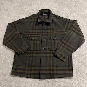 May include: A green and black plaid button-up shirt with two chest pockets. The shirt has a collared neckline and long sleeves. The plaid pattern features shades of green, black, and brown.