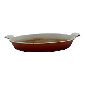 May include: An oval-shaped, orange and white enameled cast iron baking dish with two handles.
