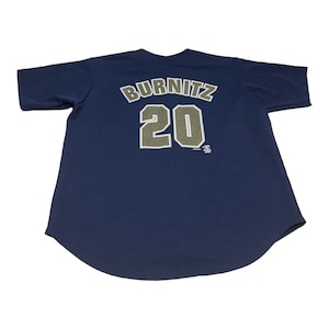 May include: Navy blue baseball jersey with the name "BURNITZ" and the number "20" printed on the back in white and olive green. The jersey has short sleeves and a rounded hem. The fabric appears to be a breathable mesh.