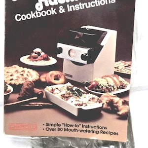 May include: A cookbook and instructions for an International Pasta & Dough Machine. The cover features the product name in white script on a dark background, with images of pasta dishes. Includes simple instructions and over 80 recipes.