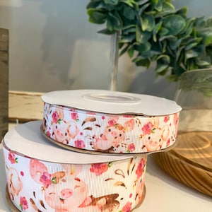 May include: Two rolls of white ribbon with a pink pig and floral pattern.