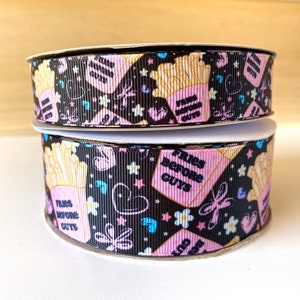 May include: Two spools of black and white ribbon with a pink and yellow print of french fries and the text "Fries Before Guys".