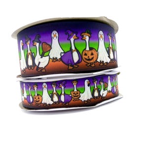 May include: Two stacked spools of grosgrain ribbon featuring a repeating pattern of white geese dressed in Halloween costumes, including ghost sheets, witch hats, and pumpkin outfits, set against a gradient background of purple, green, and orange.