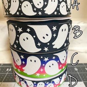 May include: Four rolls of black and white ribbon with a ghost and star pattern. The top roll has a black background, the second roll has a black background, the third roll has a rainbow gradient background, and the bottom roll has a black background.