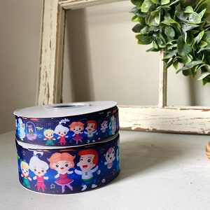 May include: Two spools of dark blue ribbon with a white background and a repeating pattern of cartoon characters. The characters are wearing colorful outfits and are set against a starry background.