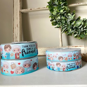 May include: Two rolls of blue ribbon with a white background and a print of cartoon characters. The ribbon has the text "Thank you for being a friend" on it.