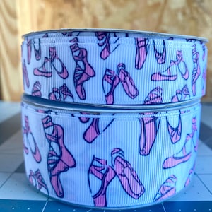 May include: Two spools of white ribbon with a pink ballet shoe pattern. The ribbon is 1.5 inches wide.