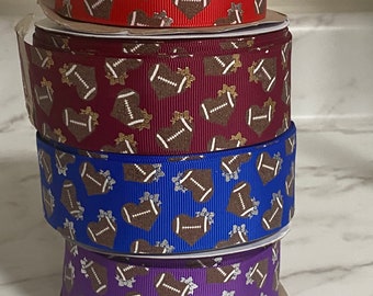 May include: Four rolls of ribbon with a football and heart pattern. The ribbons are red, burgundy, blue, and purple.