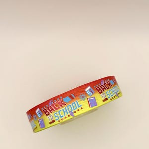 May include: A decorative ribbon featuring a red to yellow gradient background with a repeating pattern of school supplies including calculators, books, and atoms, alongside the text BACK TO SCHOOL printed in blue and red lettering.