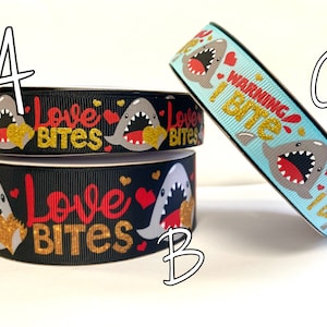 May include: Three rolls of black and blue ribbon with a shark graphic and the text "Love Bites" and "Warning I Bite" printed on them.