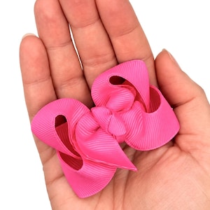 May include: A bright hot pink hair bow crafted from ribbed grosgrain ribbon. The bow features a multi-layered, looped design with a central knot, showcasing a vibrant, solid color and a distinct horizontal texture throughout the fabric.