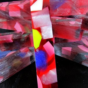 May include: A stack of clear red, pink, and white resin blanks with colorful geometric shapes and swirls. The blanks are translucent and have a glossy finish.