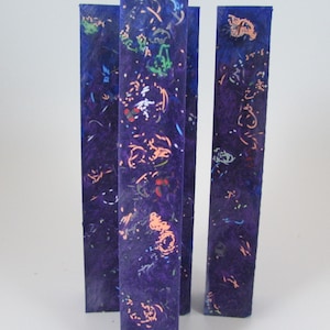 May include: Three purple and blue resin blanks with a variety of colorful flecks and swirls. The blanks are approximately 6 inches long and 1 inch wide.
