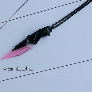 Puede incluir: Un collar de cadena negra con un colgante geométrico rosa y negro. El colgante tiene forma de cuchillo dentado.