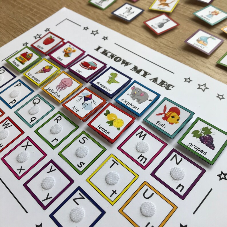 K&ouml;nnte beinhalten: Lehrreiches ABC-Lernspiel mit bunten Bildkarten und einem passenden Brett. Das Brett zeigt das Alphabet mit taktilen Punkten, und die Karten zeigen Bilder wie Apfel, Biene, Auto und Dinosaurier. Der Text "I KNOW MY ABC" ist sichtbar.