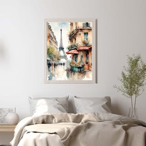 Pode incluir: Uma pintura em aguarela emoldurada que retrata uma cena de rua parisiense com a Torre Eiffel ao fundo. A obra apresenta edif&iacute;cios em tons quentes, um toldo vermelho sobre uma montra e silhuetas de pessoas a caminhar numa rua molhada.