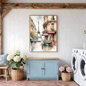 Pode incluir: Uma pintura em aquarela emoldurada retratando uma cena de rua parisiense com a Torre Eiffel ao fundo, apresentando edif&iacute;cios em tons quentes, um toldo vermelho e uma floreira, tudo renderizado em um estilo art&iacute;stico suave e cores suaves.