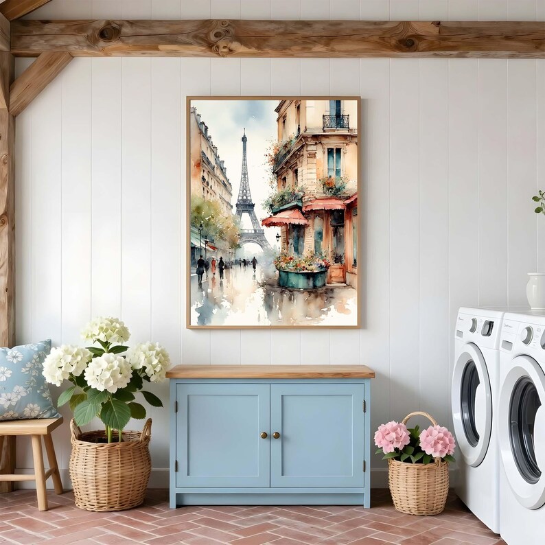 Pode incluir: Uma pintura em aquarela emoldurada retratando uma cena de rua parisiense com a Torre Eiffel ao fundo, apresentando edif&iacute;cios em tons quentes, um toldo vermelho e uma floreira, tudo renderizado em um estilo art&iacute;stico suave e cores suaves.