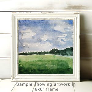 Könnte beinhalten: Aquarell-Landschaftsbild in einem weißen 15x15 cm Rahmen. Das Kunstwerk zeigt eine grüne Wiese, eine Baumreihe und einen blauen Himmel mit weißen Wolken. Der Rahmen hat einen Vintage-Look.