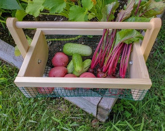 May include: A wooden carrying basket with a green mesh bottom. The basket is filled with red beets, red potatoes, and green cucumbers.