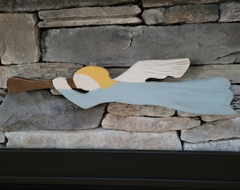 May include: A wooden angel figurine with wings, painted in light blue, white, and yellow. The angel is holding a brown trumpet in its hands.