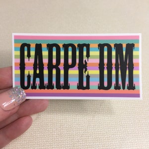 May include: A colorful sticker with the Latin phrase "Carpe Diem" in black lettering. The sticker has a rainbow striped background.