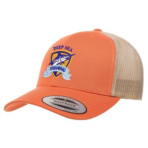 May include: Orange and beige trucker hat with a blue and yellow embroidered logo that says "Deep Sea Fishing" with a marlin fish design. The hat has a black "The Classics" Yupoong Snapback label.