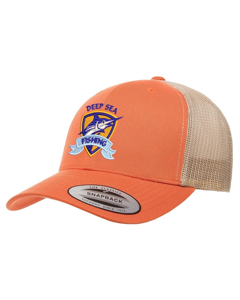 May include: Orange and beige trucker hat with a blue and yellow embroidered logo that says "Deep Sea Fishing" with a marlin fish design. The hat has a black "The Classics" Yupoong Snapback label.