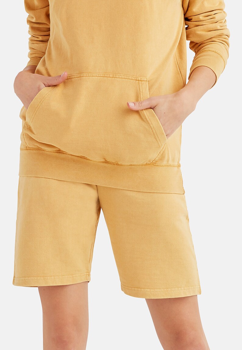 May include: A mustard yellow hoodie and matching shorts set. The hoodie has a kangaroo pocket and the shorts have a relaxed fit.