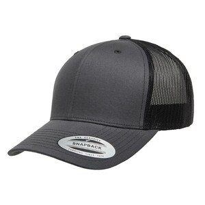 May include: A gray and black trucker hat with a mesh back. The hat has a black logo that says "The Classics" and "Snapback" with the text "Yupoong Since 1974" underneath.