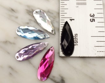 May include: Five teardrop-shaped rhinestones in various colors, including clear, light blue, purple, pink, and black. The rhinestones are approximately 1 inch long and are arranged in a semi-circle.