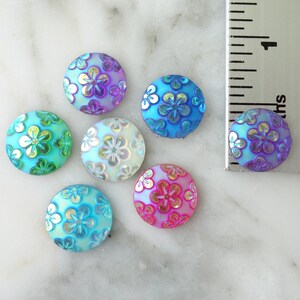 May include: Six iridescent flower-shaped buttons in various colors, including purple, blue, green, and pink. The buttons are approximately 1 inch in diameter.