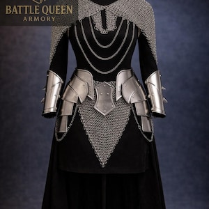 May include: A medieval armour set displayed on a black dress form. The armour includes a chainmail cape, metal shoulder and arm guards, and a waist belt. The set is against a dark blue background. The text "BATTLE QUEEN ARMORY" is visible.