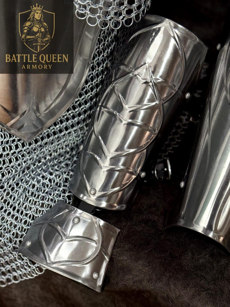 May include: Close-up of polished silver arm armor with leaf-like designs. The armor is part of a set, with chainmail visible in the background. The Battle Queen Armory logo is in the upper left corner.