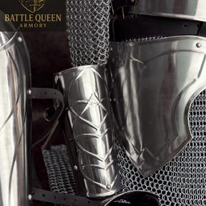May include: Close-up of medieval armor components, including a polished metal arm guard with a leaf design, a chainmail shirt, and a shoulder plate. The image features the "Battle Queen Armory" logo in the upper left corner.