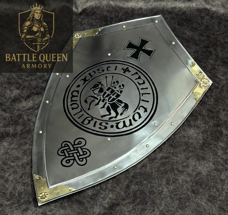 Puede incluir: Un escudo plateado con una cruz negra y un emblema circular con dos caballeros a caballo. El escudo tiene esquinas de lat&oacute;n y es de Battle Queen Armory.