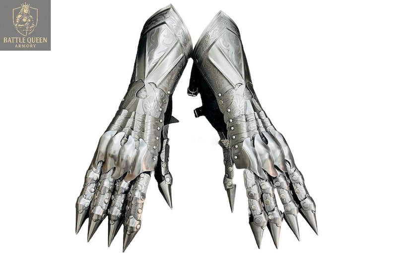 May include: Two silver metal gauntlets with articulated fingers and claw-like tips. The armour has engraved details and is designed to protect the hands and forearms. The Battle Queen Armory logo is in the upper left corner.